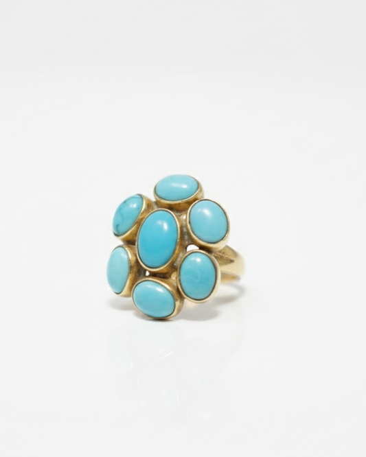 A gold ring featuring a cluster of oval-shaped light blue turquoise stones, photographed on a clean white background.