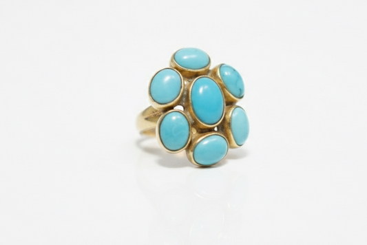Gold ring with turquoise stones on a white background